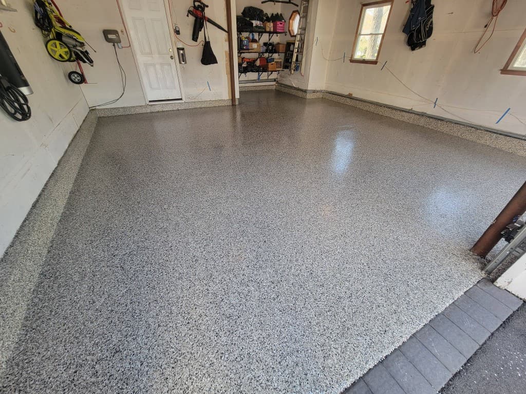 Polyaspartic topcoat over full-broadcast flake — mirror-gloss finish on residential garage, Long Island NY